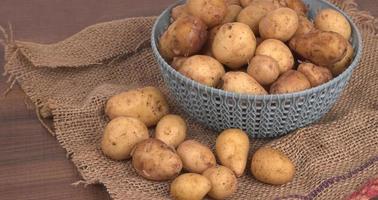 Fresh small potatoes for cooking in a wooden bowl. With copy space  on white background. photo