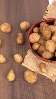 Fresh small potatoes for cooking in a wooden bowl. With copy space  on white background. photo