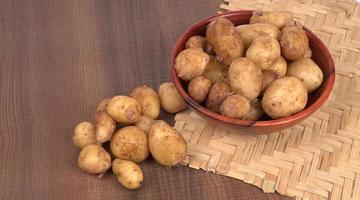 Fresh small potatoes for cooking in a wooden bowl. With copy space  on white background. photo