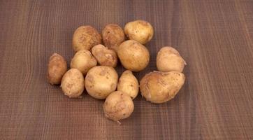 Fresh small potatoes for cooking in a wooden bowl. With copy space  on white background. photo