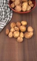 Fresh small potatoes for cooking in a wooden bowl. With copy space  on white background. photo