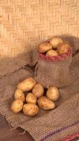 Fresh small potatoes for cooking in a wooden bowl. With copy space  on white background. photo