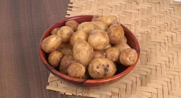 Fresh small potatoes for cooking in a wooden bowl. With copy space  on white background. photo