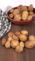 Fresh small potatoes for cooking in a wooden bowl. With copy space  on white background. photo