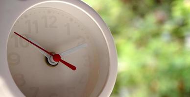 A closeup shot of a white clock with arrows showing time. photo