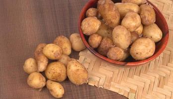 Fresh small potatoes for cooking in a wooden bowl. With copy space  on white background. photo