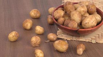 Fresh small potatoes for cooking in a wooden bowl. With copy space  on white background. photo