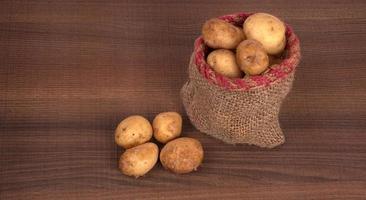 Fresh small potatoes for cooking in a wooden bowl. With copy space  on white background.