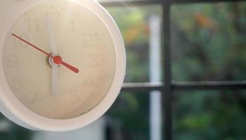 A closeup shot of a white clock with arrows showing time. photo