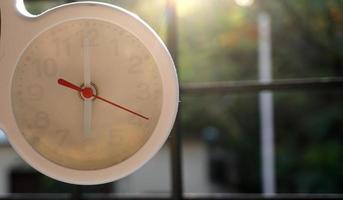 A closeup shot of a white clock with arrows showing time. photo