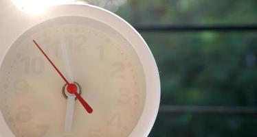 A closeup shot of a white clock with arrows showing time. photo