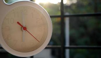 A closeup shot of a white clock with arrows showing time. photo