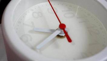 A closeup shot of a white clock with arrows showing time. photo