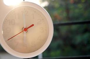 A closeup shot of a white clock with arrows showing time. photo