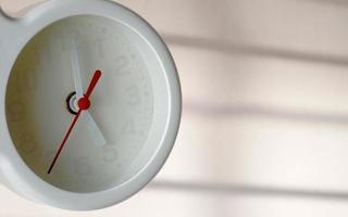 A closeup shot of a white clock with arrows showing time. photo