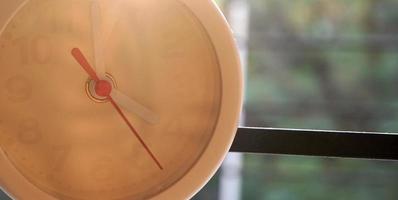 A closeup shot of a white clock with arrows showing time. photo