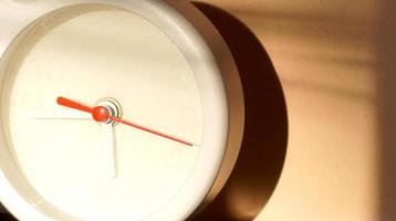 A closeup shot of a white clock with arrows showing time. photo