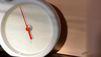 A closeup shot of a white clock with arrows showing time. photo