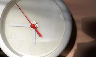 A closeup shot of a white clock with arrows showing time. photo