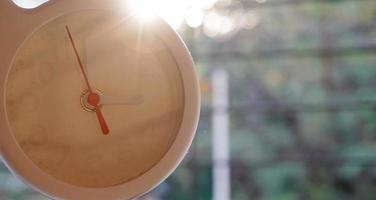 A closeup shot of a white clock with arrows showing time. photo