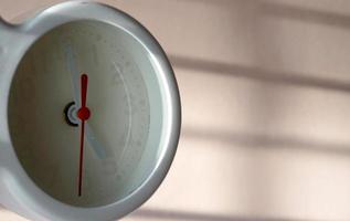 A closeup shot of a white clock with arrows showing time. photo