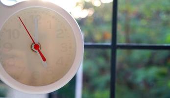 A closeup shot of a white clock with arrows showing time. photo