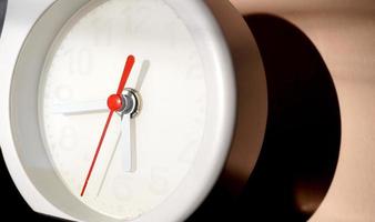 A closeup shot of a white clock with arrows showing time. photo