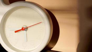 A closeup shot of a white clock with arrows showing time. photo