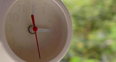 A closeup shot of a white clock with arrows showing time. photo