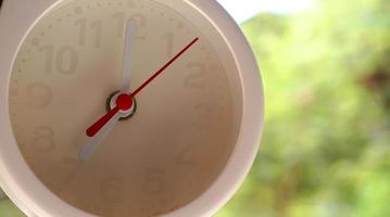 A closeup shot of a white clock with arrows showing time. photo