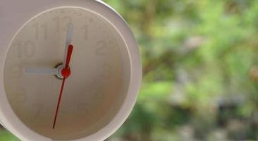 A closeup shot of a white clock with arrows showing time. photo