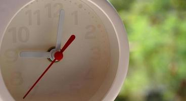 A closeup shot of a white clock with arrows showing time. photo