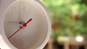 A closeup shot of a white clock with arrows showing time. photo