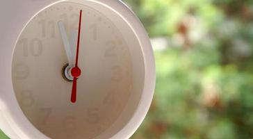 A closeup shot of a white clock with arrows showing time. photo