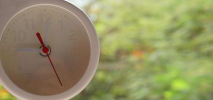 A closeup shot of a white clock with arrows showing time. photo