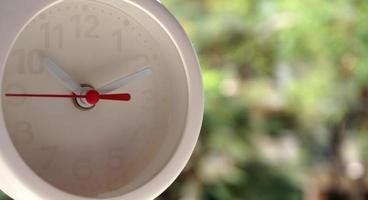 A closeup shot of a white clock with arrows showing time. photo