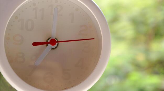 A closeup shot of a white clock with arrows showing time. photo