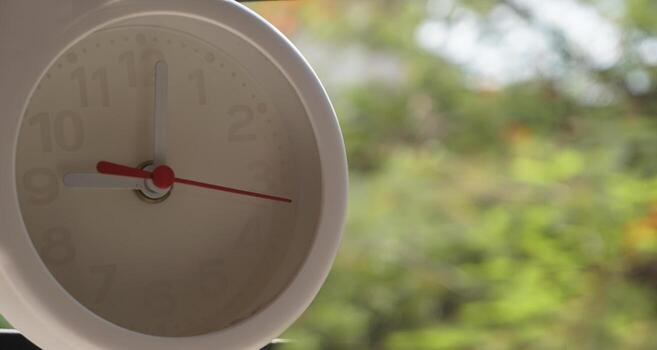 A closeup shot of a white clock with arrows showing time. photo