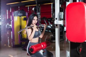 Fitness Asian women performing doing exercises training the shoulder and chest muscles in sport gym interior and health club. photo
