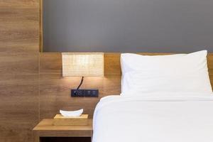 primer plano de la almohada blanca en la decoración de la cama con lámpara de luz y caja de pañuelos en el interior de la habitación del hotel. foto