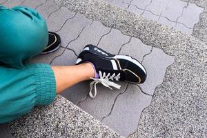 The legs and shoes of a girl sitting on the concrete steps photo