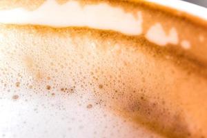 Media taza de café con leche caliente y espuma suave en taza de cerámica blanca. foto