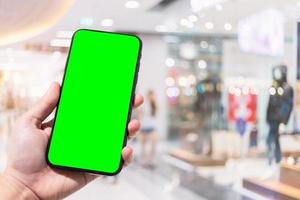 Primer plano de uso femenino smartphone borrosa imágenes en el centro comercial y tienda de ropa desenfoque del fondo. foto