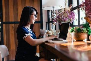 Asian business female hold a coffee mug working with laptop in coffee shop like the background. photo