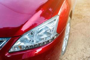 Closeup of headlight of red car outdoors. photo