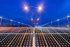 Textura de panel solar de paneles fotovoltaicos con luz nocturna de la ciudad en la carretera en el fondo de la noche, concepto de energía alternativa.