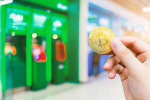 Use hand holding Bitcoin coin blurred images of Abstract blur in Blurred of ATM machine blue in Department store,Cryptocurrency concept of electronic payments. photo