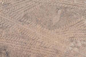 Car wheel on a dirt road on the brown dry soil ground texture background. photo