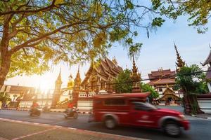 old city moat to busy street with many red taxi and temple of the evening in Chiang Mai,Thailand.