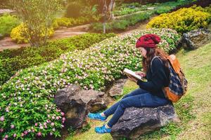 woman travel nature in the flower garden. relax sitting on rocks and reading books In the midst of nature at national park doi Inthanon. photo